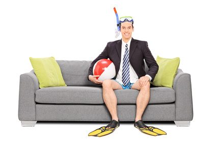 Man with snorkel and business suit seated on sofa isolated on white background